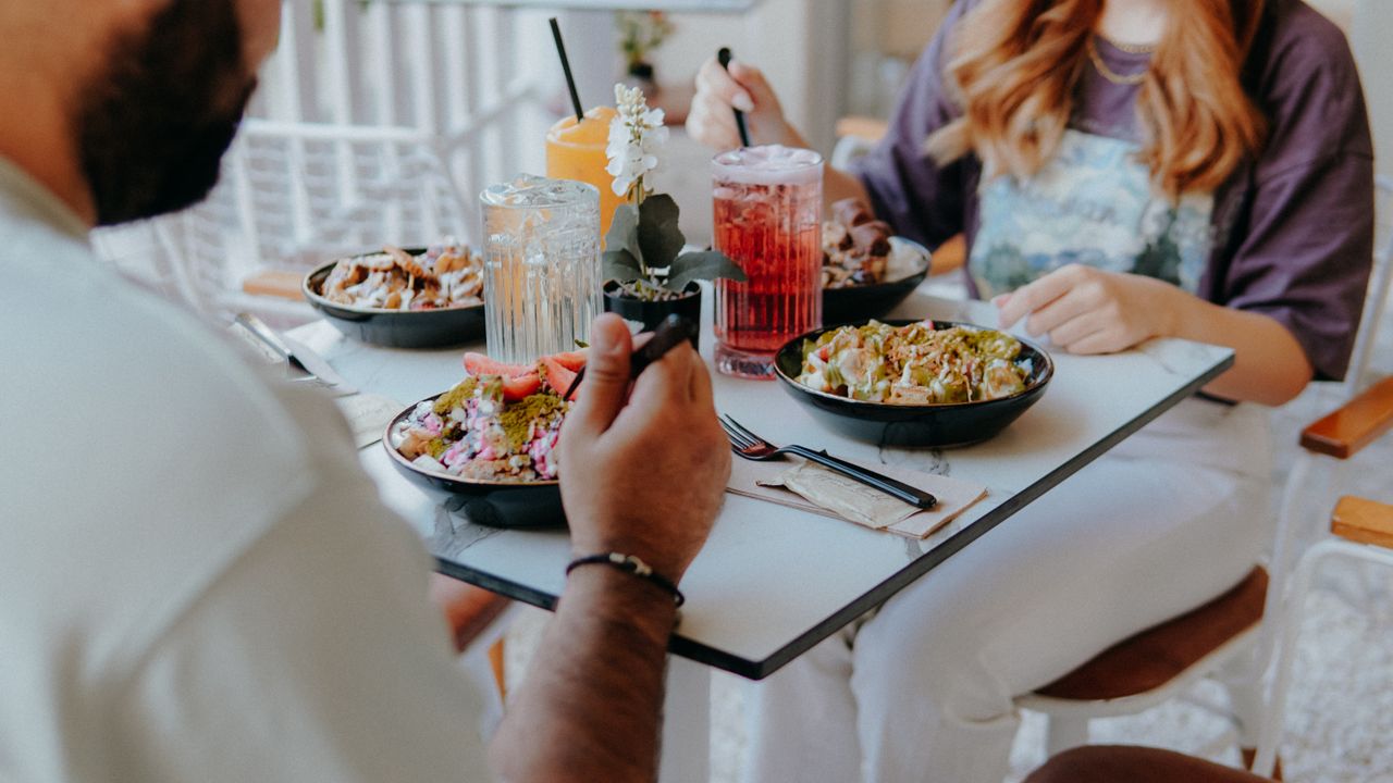 Group enjoying healthy food bowls at a modern cafe setting with refreshing drinks.